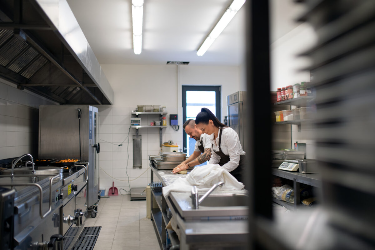 Chef and cook working on their dishes indoors in restaurant kitchen with a Chef De partie 