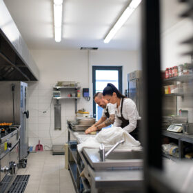 Chef and cook working on their dishes indoors in restaurant kitchen with a Chef De partie
