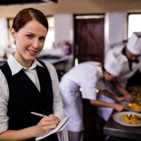 waiter giving order to chefs in the kitchen in a hotel during work