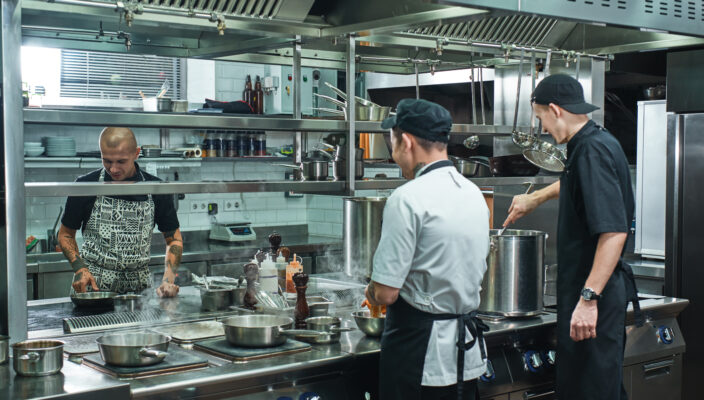 Cooking process. Freelance agency chef and two young Chef preparing food in a restaurant kitchen